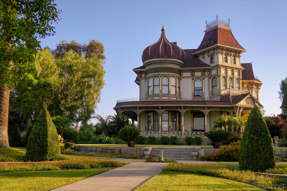 a victorian house in Redlands with green trees and blue sky