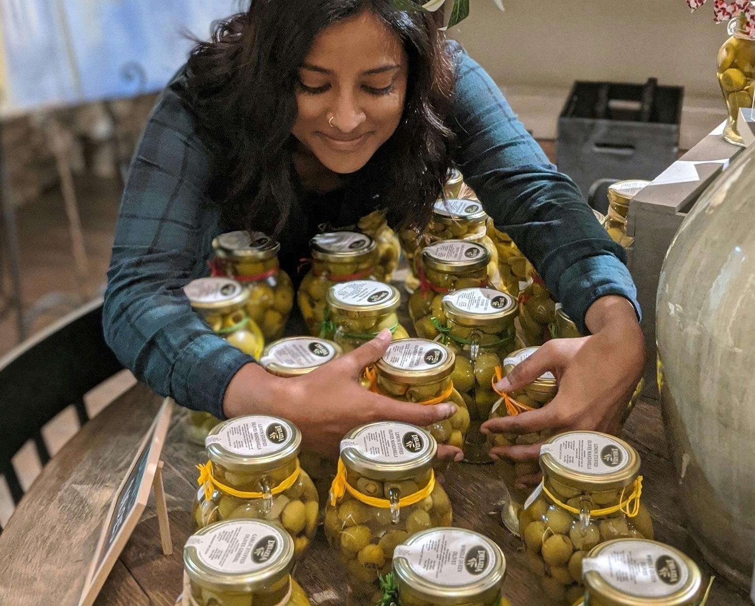 Employee, Nina, and jars of olives Lot22 carries to be paired with their oils and vinegars.