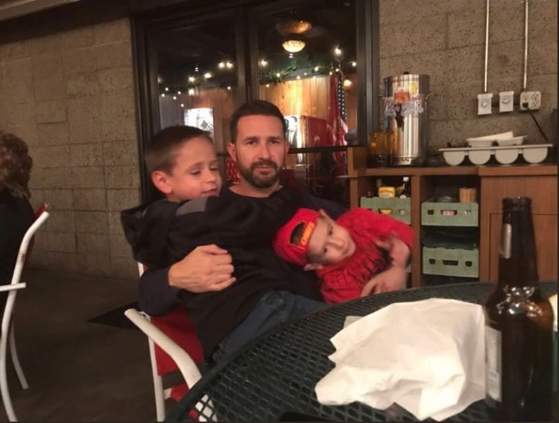 A dad and two kids sitting on a patio at a restaurant